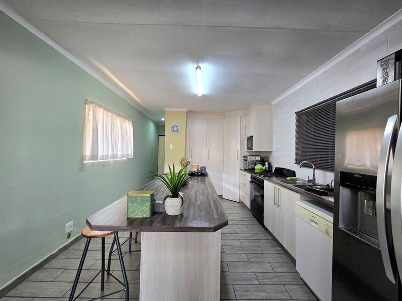 A functional kitchen featuring a central island, laminate countertops, built-in cabinetry, and tiled flooring, offering a practical layout for cooking and dining.