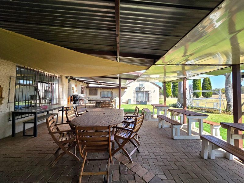 Spacious covered outdoor patio featuring brick paving and a corrugated metal roof, providing a functional area for outdoor dining and entertainment.