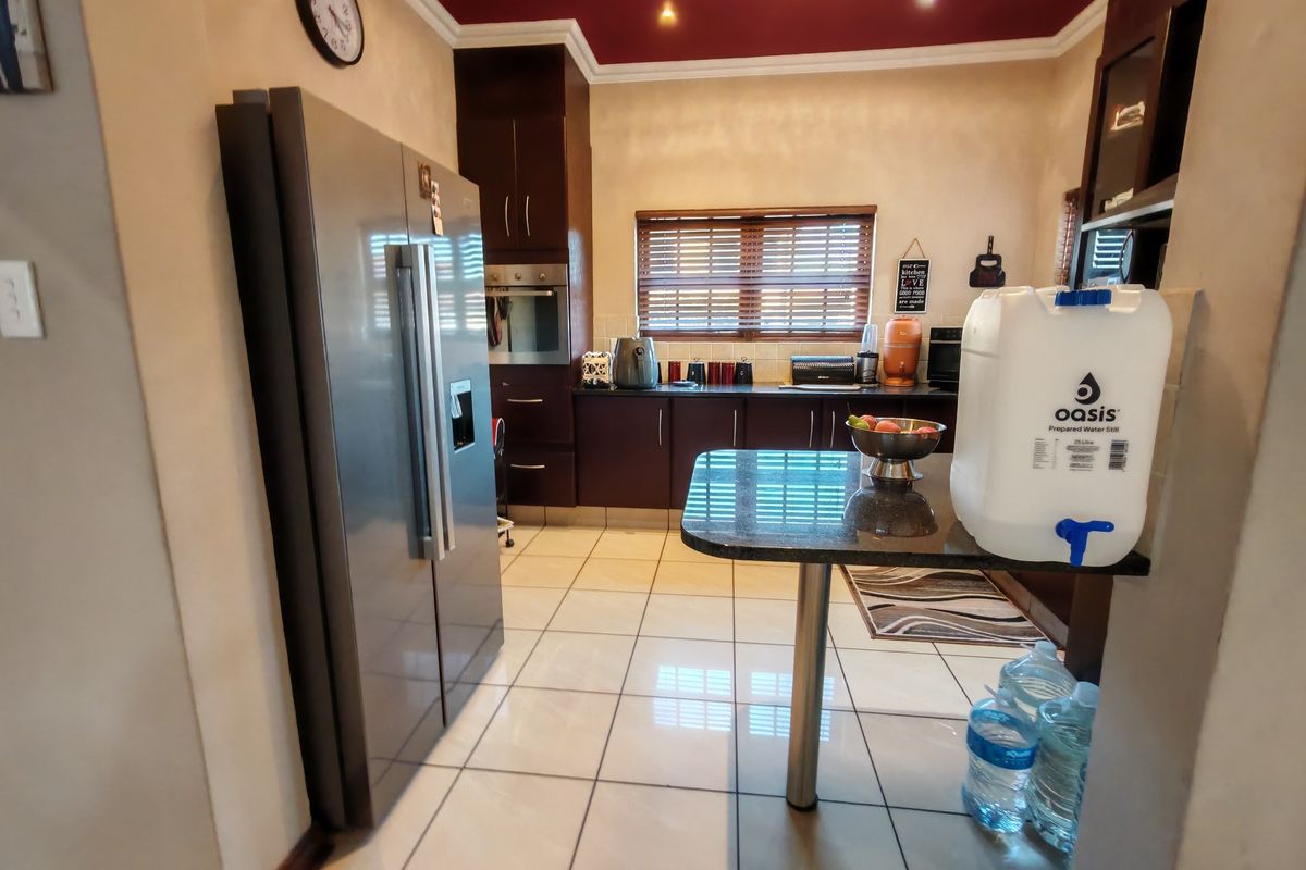 A functional kitchen featuring dark wood cabinetry, granite countertops, built-in oven, and tiled flooring with a breakfast nook area.