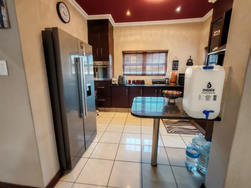 A functional kitchen featuring dark wood cabinetry, granite countertops, built-in oven, and tiled flooring with a breakfast nook area.