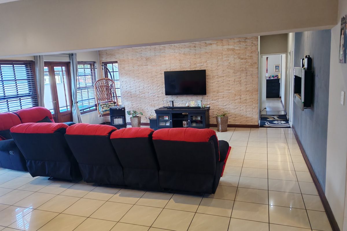 Spacious living room featuring a textured stone accent wall, neutral ceramic floor tiles, and direct access to the outdoor area through sliding glass doors.