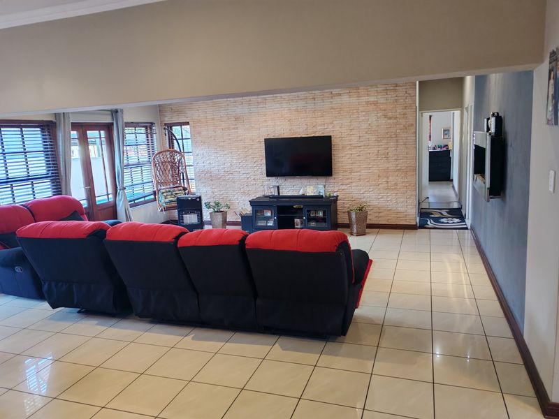 Spacious living room featuring a textured stone accent wall, neutral ceramic floor tiles, and direct access to the outdoor area through sliding glass doors.