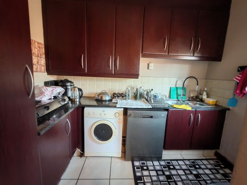 A functional kitchen featuring dark wood cabinetry, granite countertops, tiled backsplash, and integrated dishwasher, providing a practical workspace for daily meal preparation.