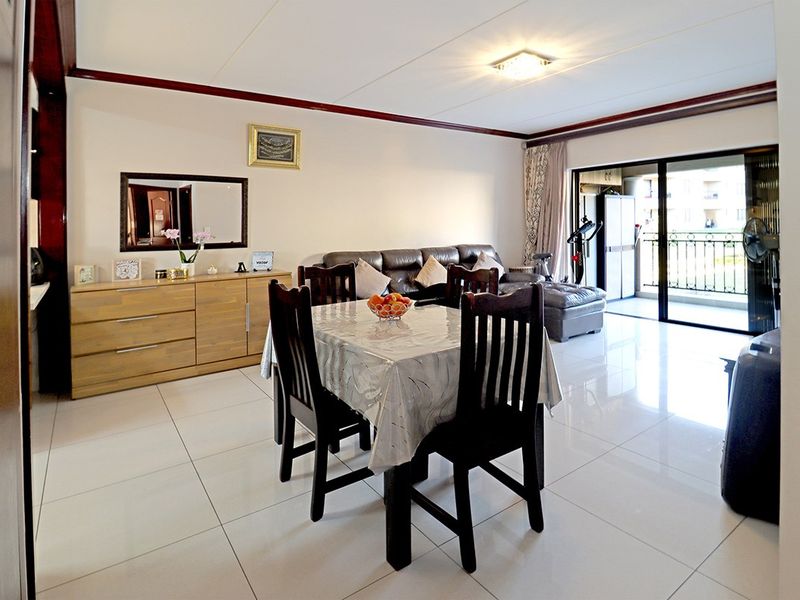 Spacious open-plan living and dining area featuring large white floor tiles and sliding glass doors leading to a private balcony.