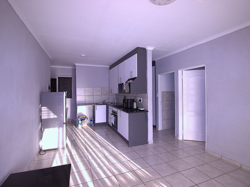 Open plan kitchen area featuring tiled flooring, built-in cabinetry, and a tiled backsplash, providing a functional layout for the apartment.