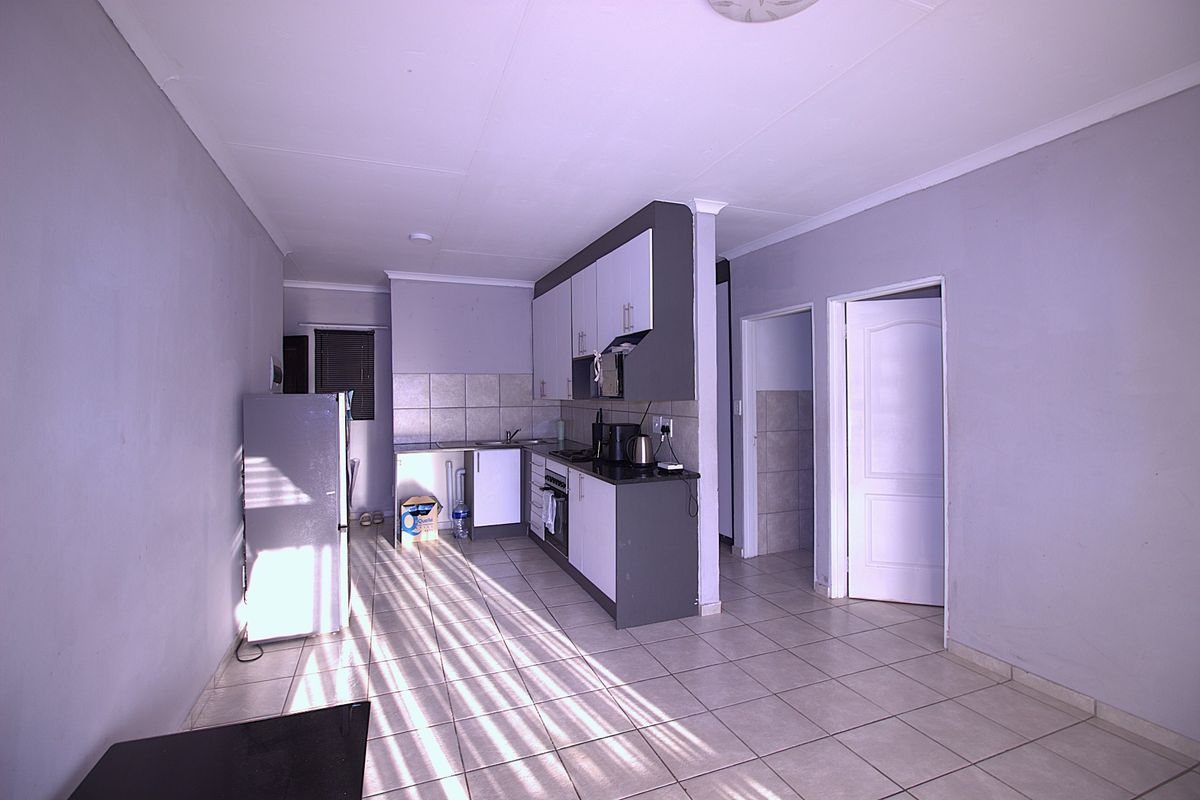 Open plan kitchen area featuring tiled flooring, built-in cabinetry, and a tiled backsplash, providing a functional layout for the apartment.