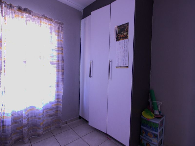 A bedroom featuring tiled flooring and a built-in wardrobe with white doors, providing functional storage space.