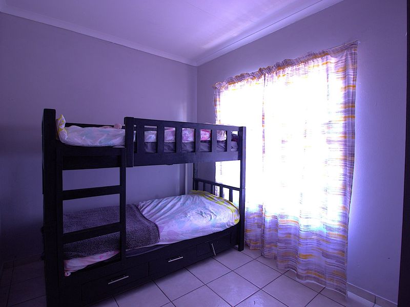 A bedroom featuring tiled flooring and a window with a curtain rod, providing a functional space for rest.