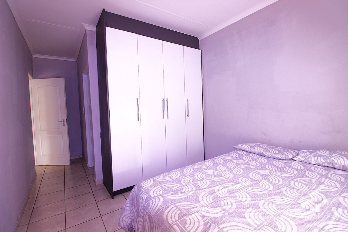 A bedroom featuring a large built-in wardrobe with white doors and tiled flooring.