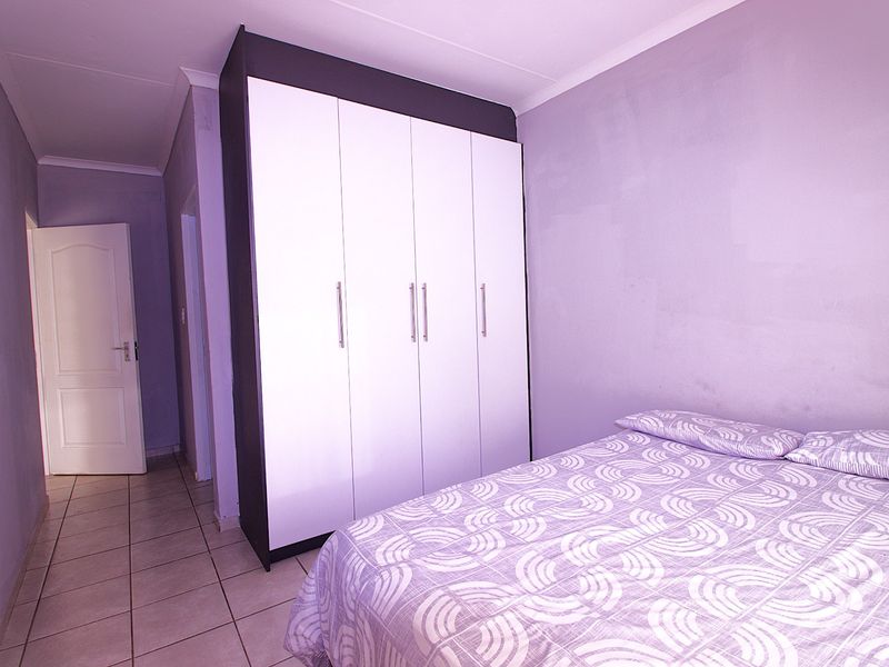 A bedroom featuring a large built-in wardrobe with white doors and tiled flooring.