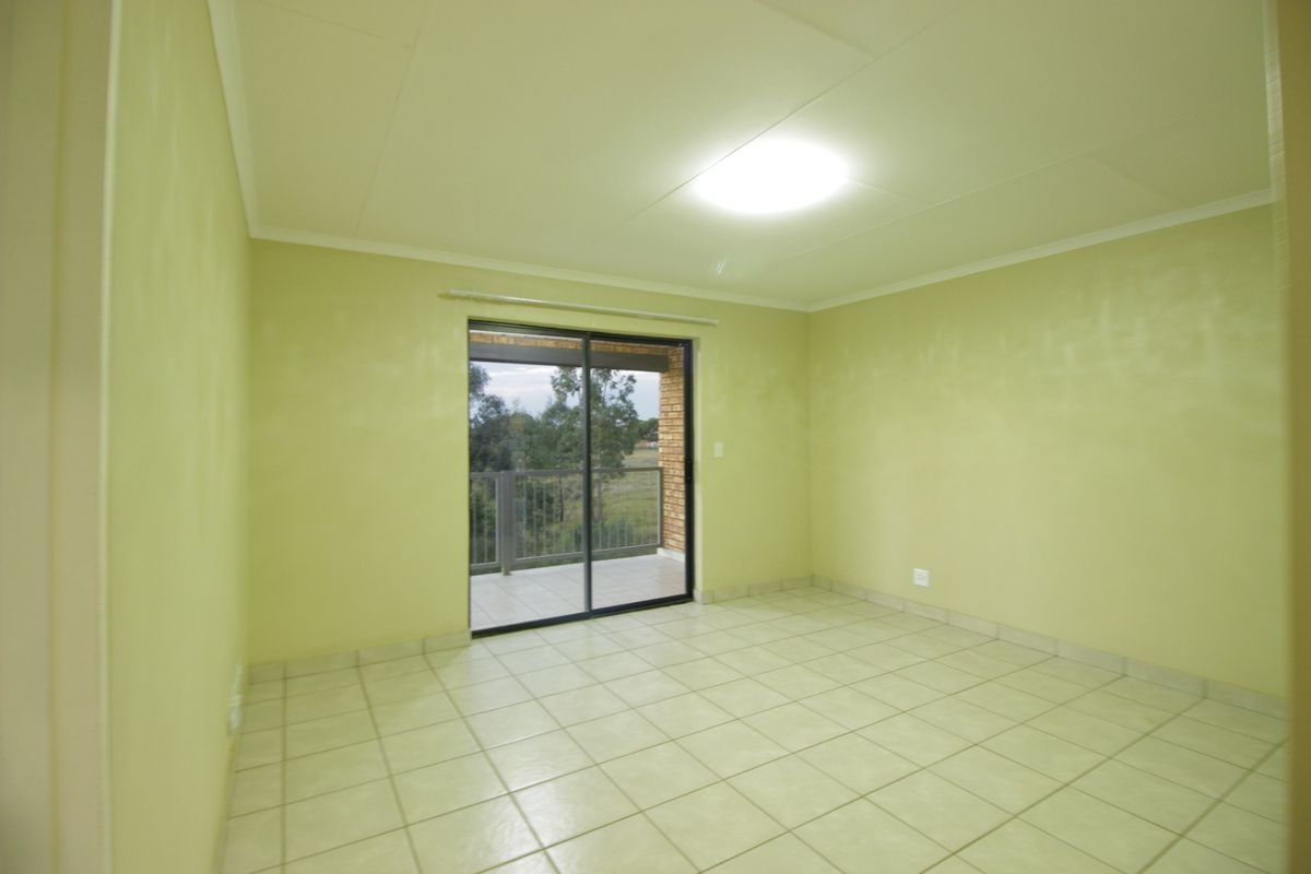 An empty bedroom featuring ceramic floor tiles, a sliding glass door leading to a balcony, and a neutral paint finish.