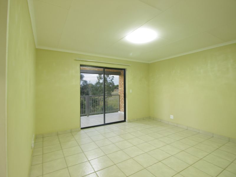 An empty bedroom featuring ceramic floor tiles, a sliding glass door leading to a balcony, and a neutral paint finish.