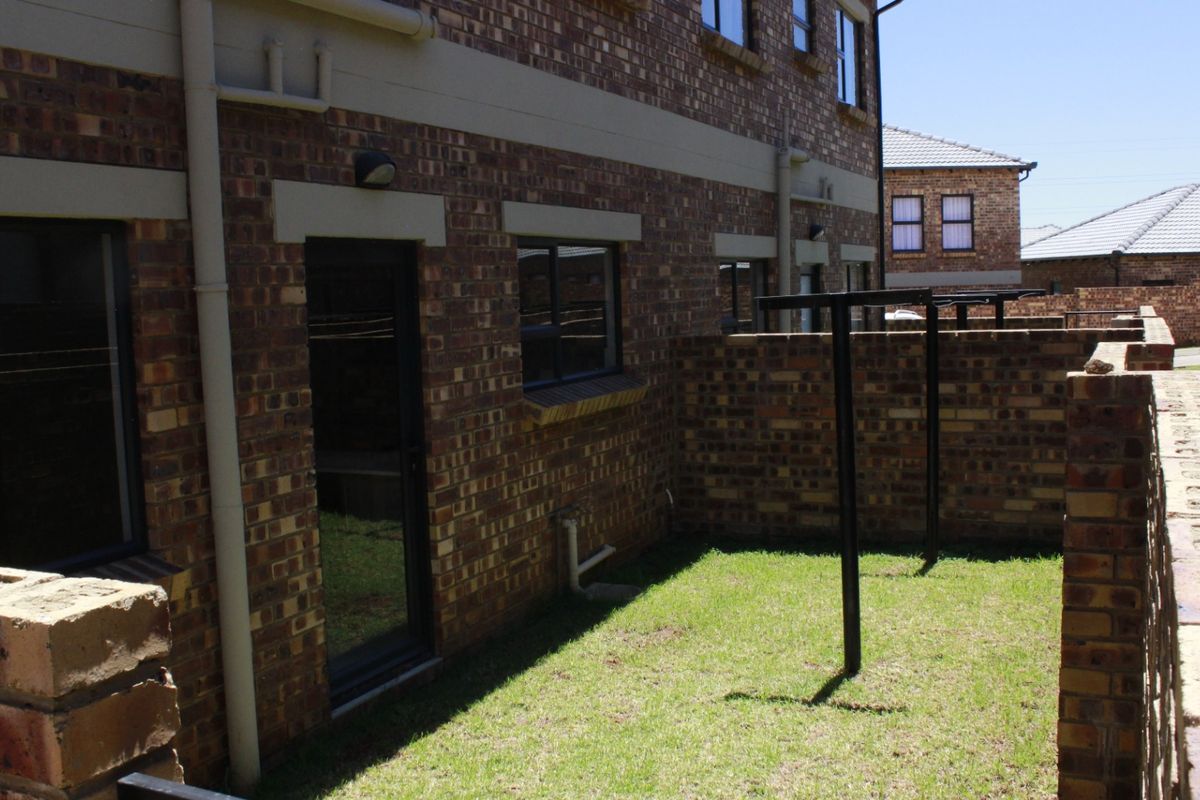 A private rear garden area featuring face brick exterior walls, a boundary wall, and a fixed washing line.