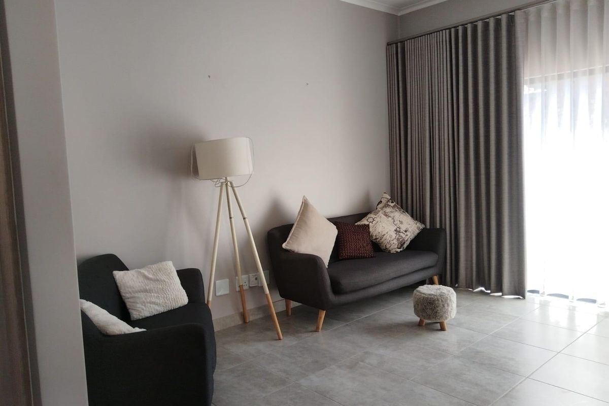 A well-maintained living room featuring neutral grey tiled flooring and full-length curtains, providing a clean and modern aesthetic.
