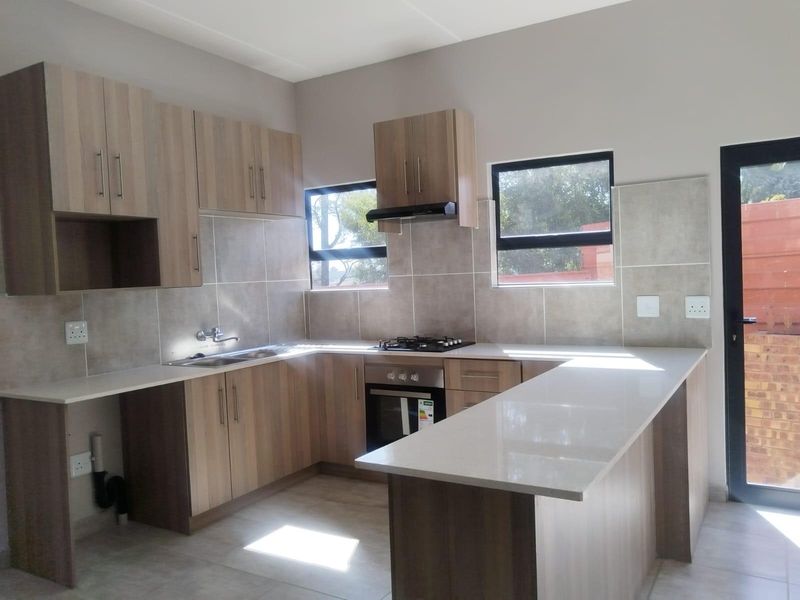 Modern kitchen featuring light wood-grain cabinetry, stone countertops, built-in oven, gas hob, and a functional breakfast bar layout.