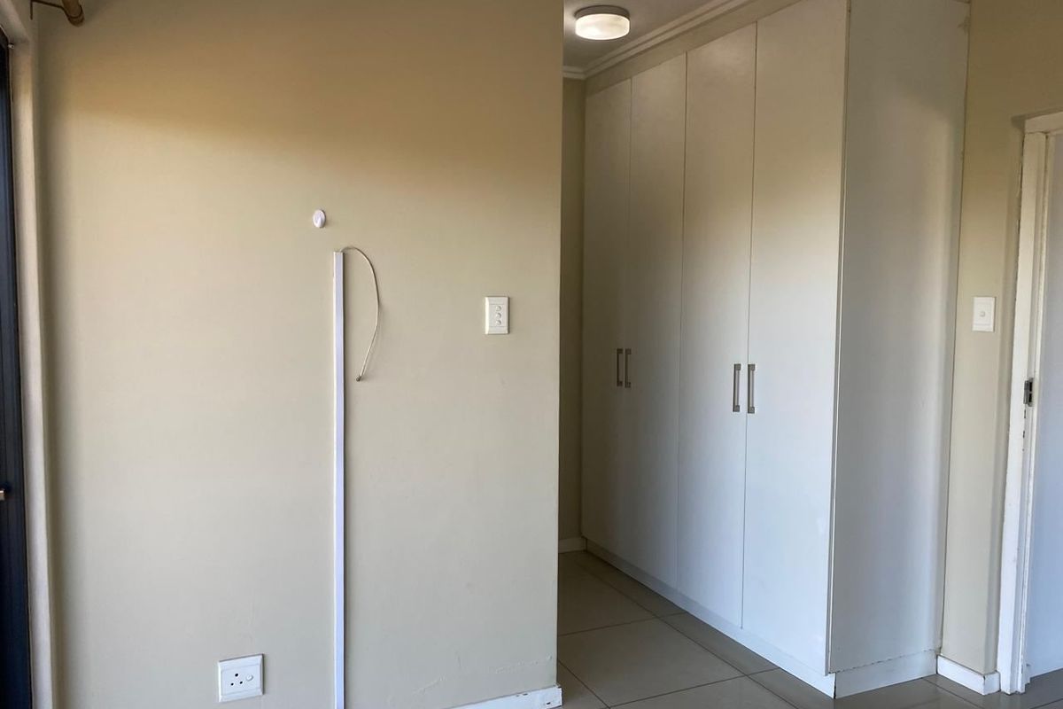 A bedroom interior featuring built-in cupboards, tiled flooring, and neutral wall tones, currently vacant and ready for personalization.