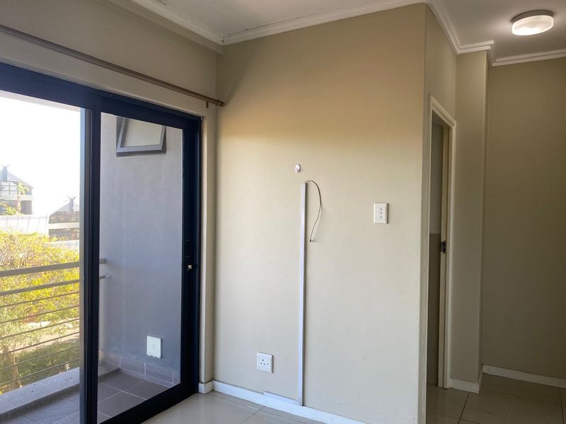 An empty living area featuring tiled floors, a sliding glass door leading to a balcony, and neutral wall finishes.