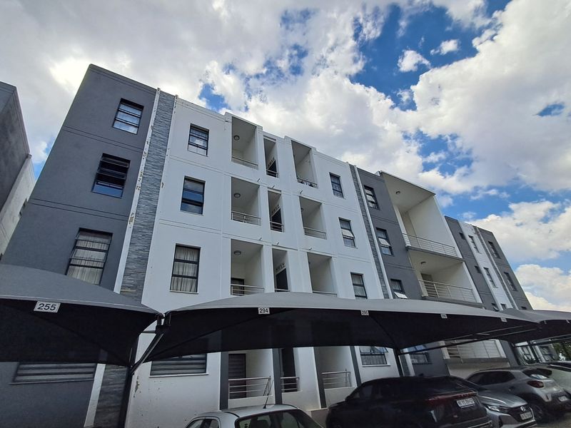 Exterior view of a modern multi-story apartment complex featuring private balconies, aluminium windows, and dedicated shade cloth parking bays.