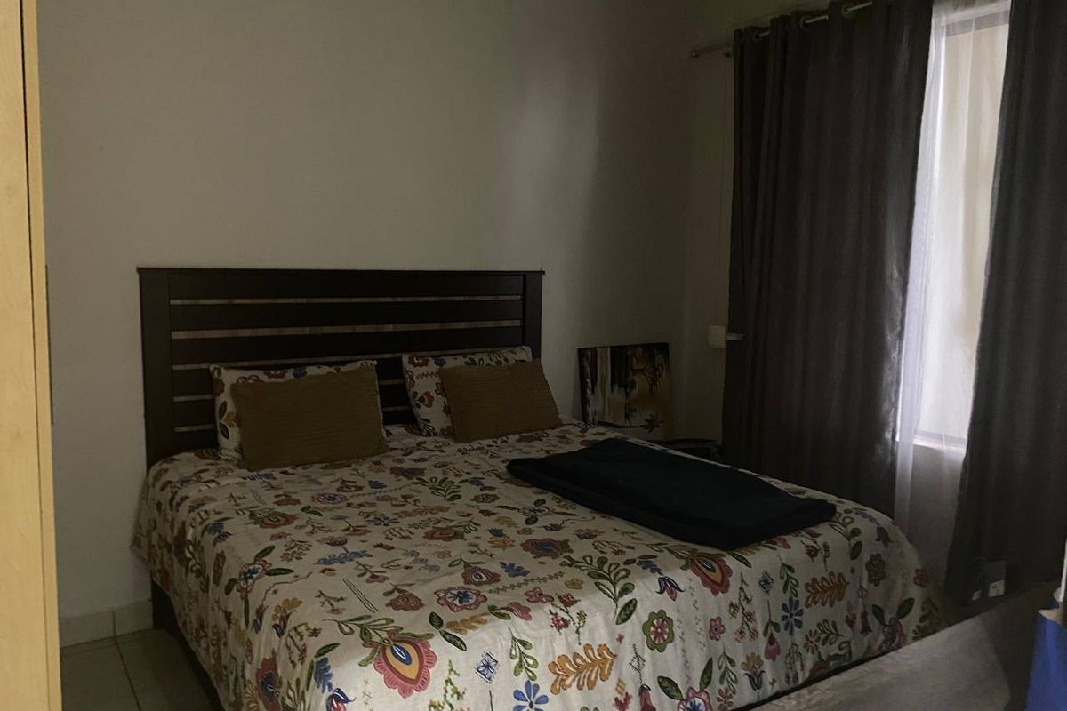A bedroom featuring tiled flooring and window treatments, providing a functional sleeping space.