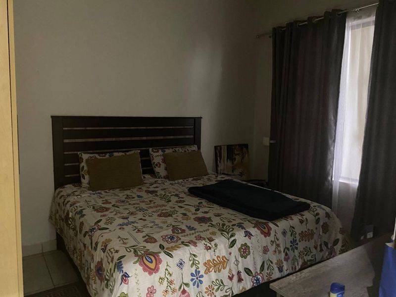 A bedroom featuring tiled flooring and window treatments, providing a functional sleeping space.