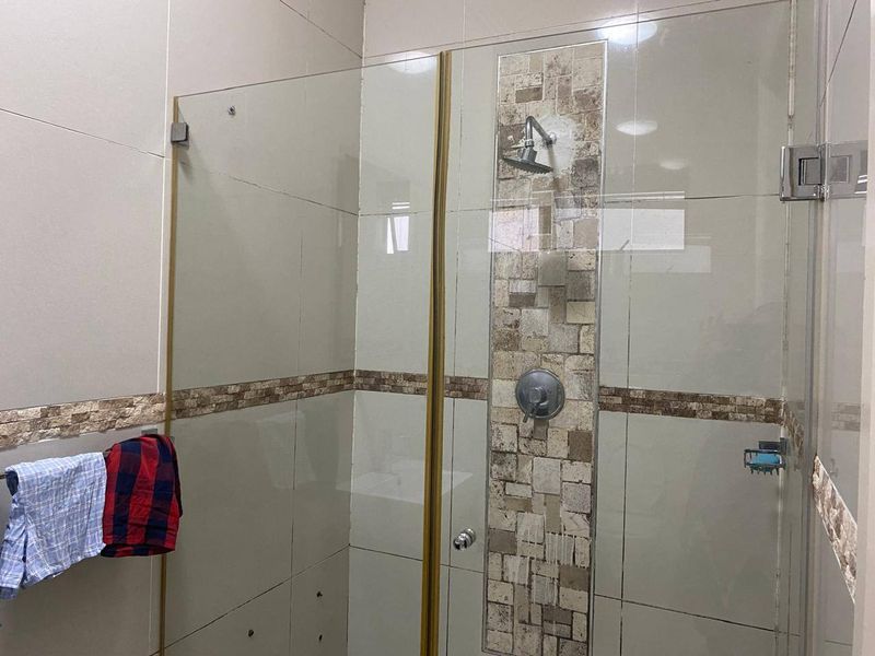 A bathroom shower enclosure featuring glass panels and decorative stone tile accents on the wall.
