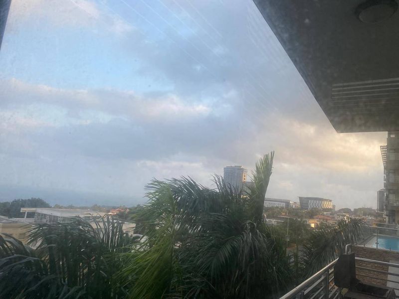An elevated view from an apartment balcony overlooking the surrounding neighbourhood and cityscape under a cloudy sky.