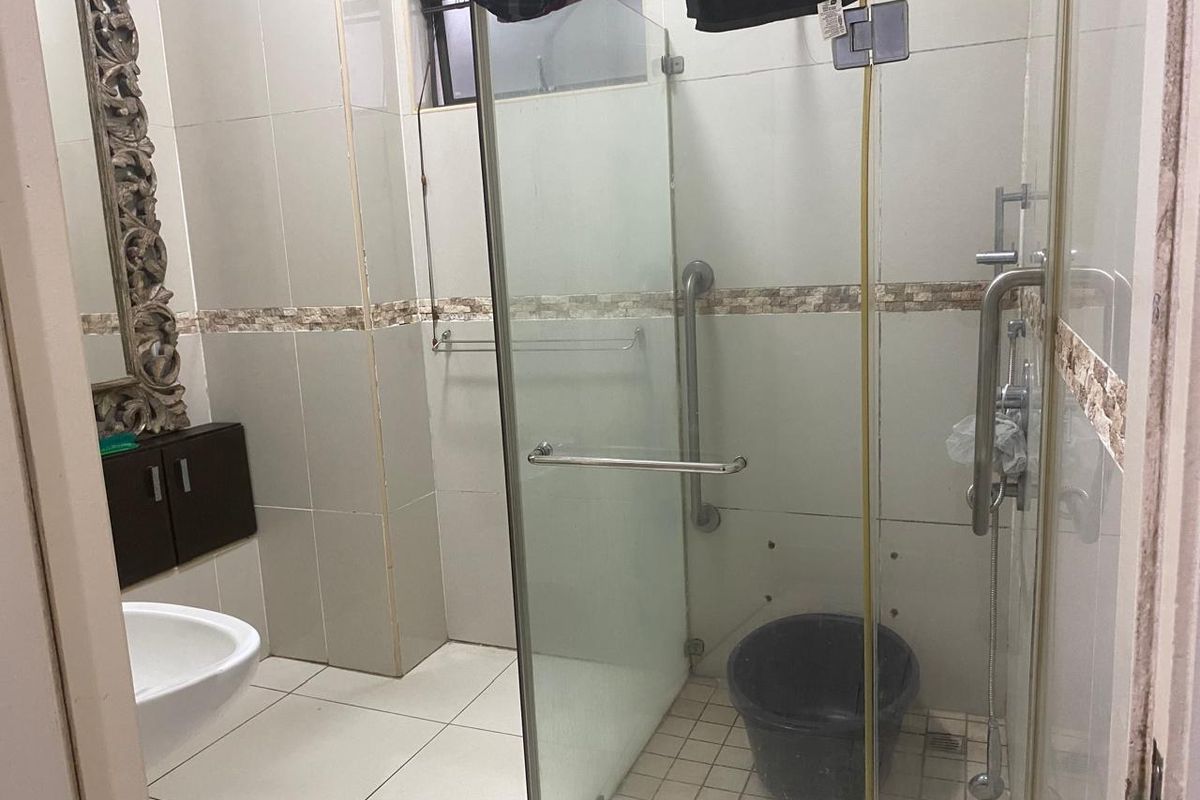 A bathroom featuring a glass-enclosed shower with grab rails, tiled finishes, and a wall-mounted vanity cabinet, requiring some maintenance and repair.