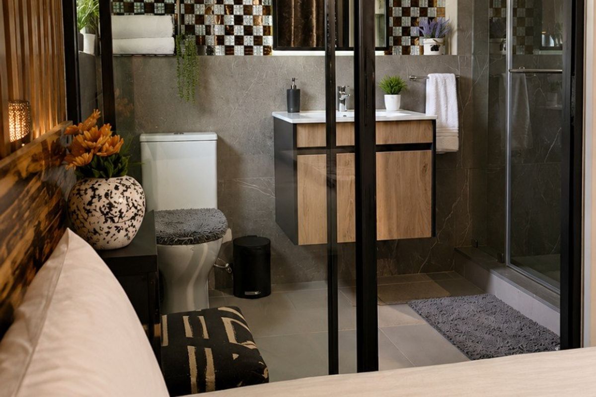 Modern en-suite bathroom featuring a glass partition, vanity cabinet, and walk-in shower, conveniently accessible from the bedroom.