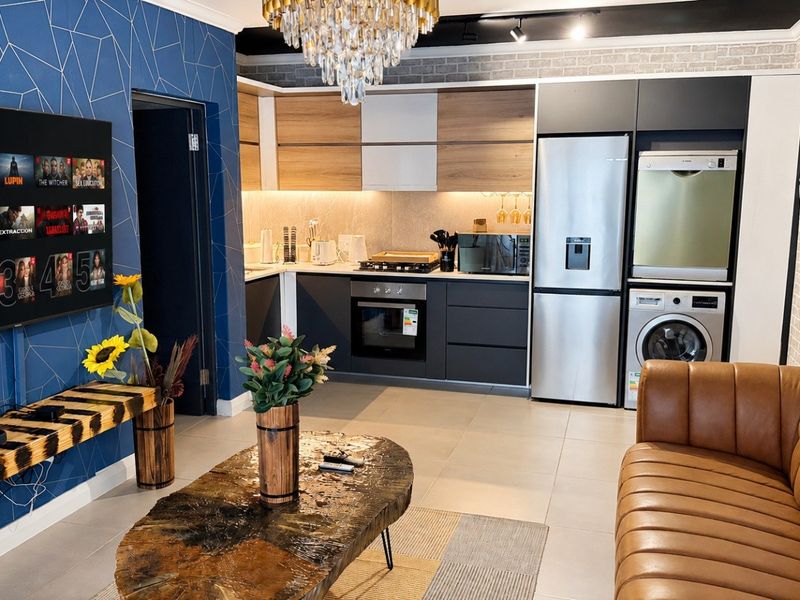 Modern open-plan living area featuring a contemporary kitchen with sleek cabinetry, integrated appliances, and stylish geometric wall accents.