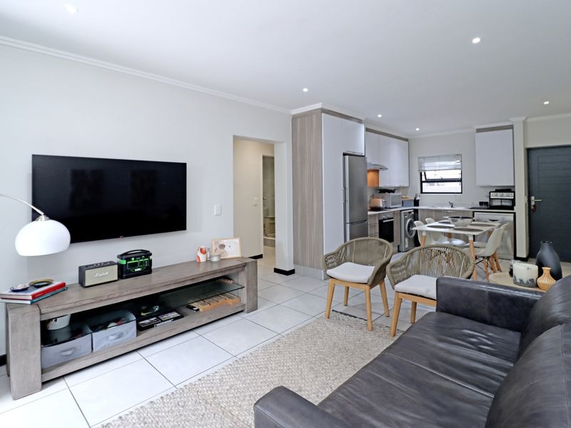 Modern open-plan living area featuring tiled floors, recessed lighting, and a contemporary kitchen with built-in cabinetry and integrated appliances.