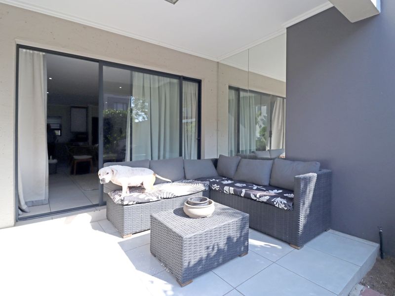 A covered patio area featuring tiled flooring, large sliding glass doors providing access to the interior, and a decorative mirrored wall panel.