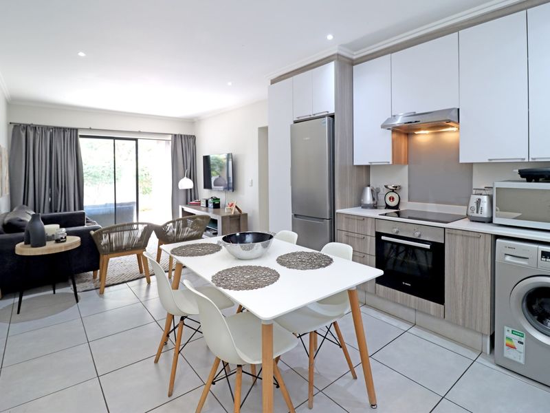 Modern open-plan living area featuring a contemporary kitchen with built-in appliances, tiled flooring, and seamless access to the outdoor patio through sliding doors.