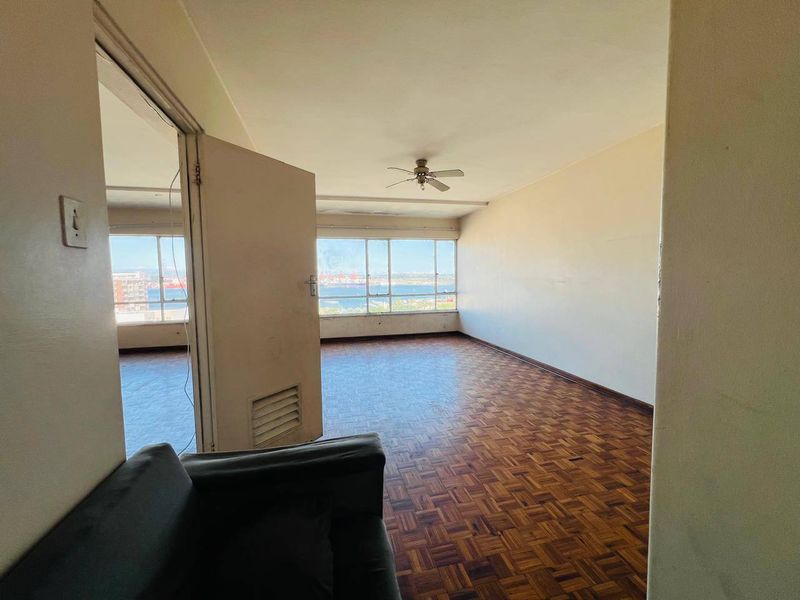 Spacious living area featuring original parquet flooring, a ceiling fan, and large windows offering expansive views.