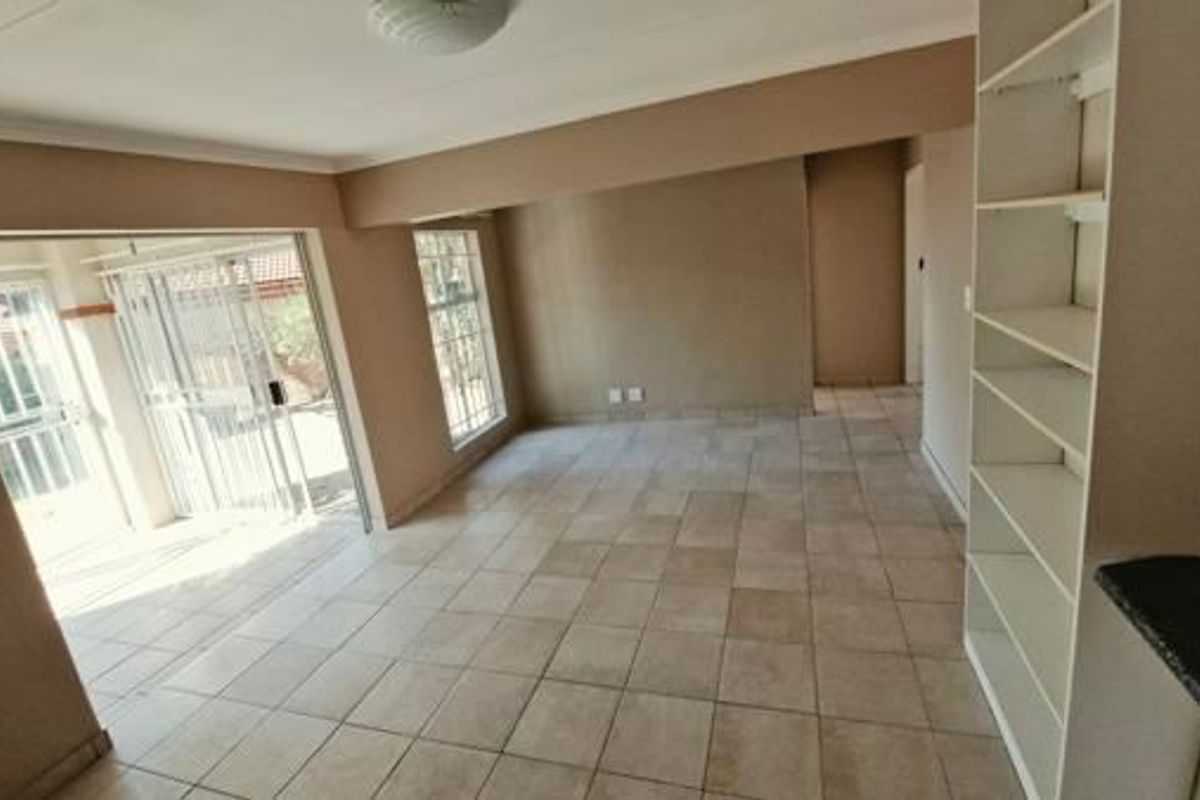 An open-plan living area featuring tiled flooring, built-in shelving, and a sliding glass door providing access to the exterior.