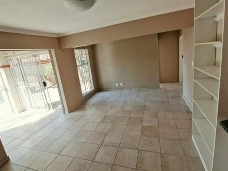 An open-plan living area featuring tiled flooring, built-in shelving, and a sliding glass door providing access to the exterior.