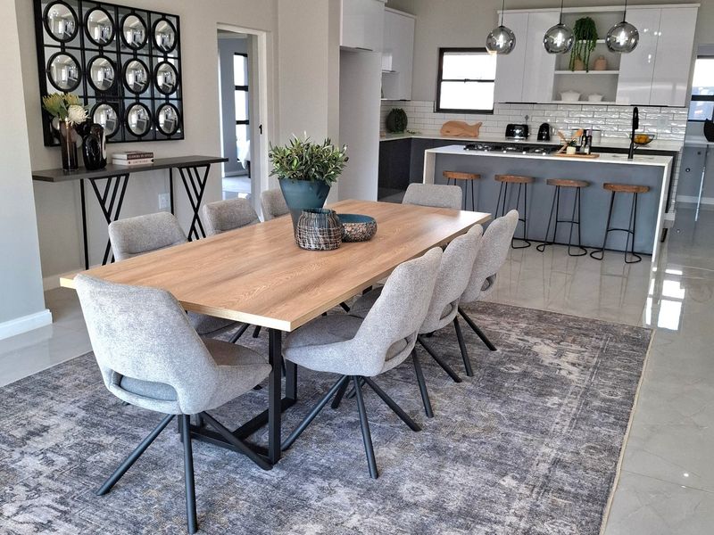 Modern open-plan dining and kitchen area featuring a central island, sleek cabinetry, contemporary pendant lighting, and polished tiled flooring throughout.