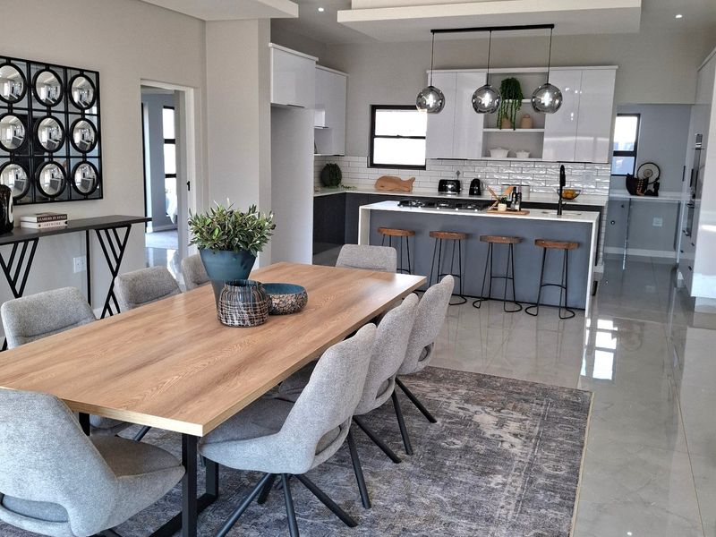 Modern open-plan living and dining area featuring a sleek kitchen with a central island, high-gloss cabinetry, and contemporary lighting fixtures.