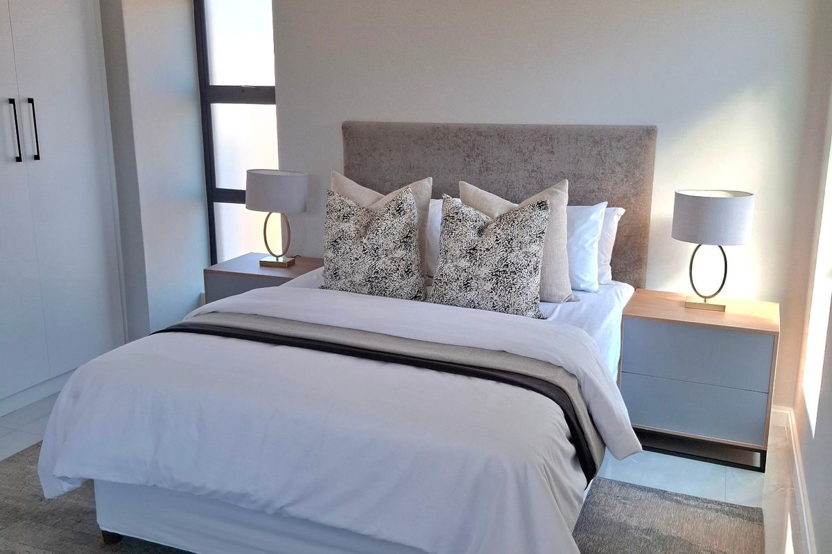 A modern, well-maintained bedroom featuring built-in wardrobes, recessed lighting, and neutral tiled flooring.