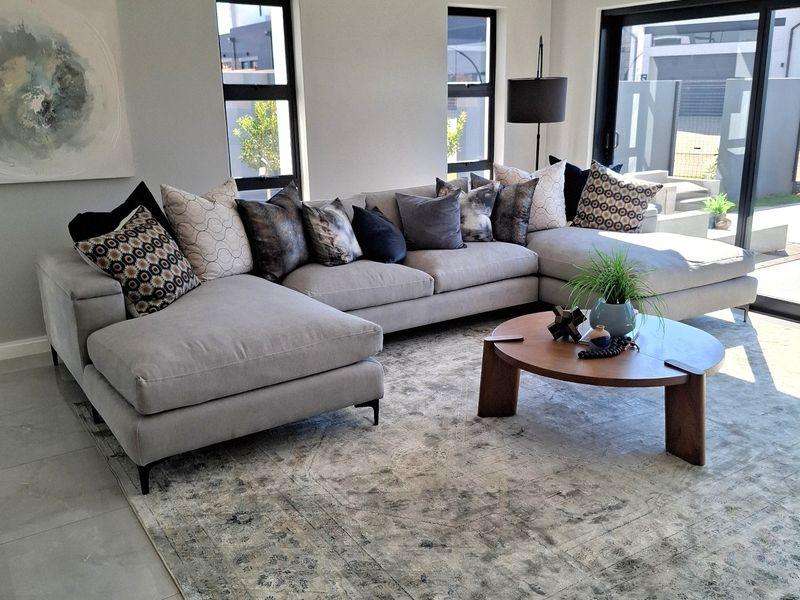 Modern living room featuring a recessed ceiling, large aluminium-framed windows, and sliding glass doors leading to the exterior, finished with neutral tiled flooring.