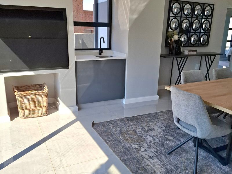 Modern open-plan living area featuring tiled flooring, a built-in fireplace, and a convenient kitchenette nook with a sink.