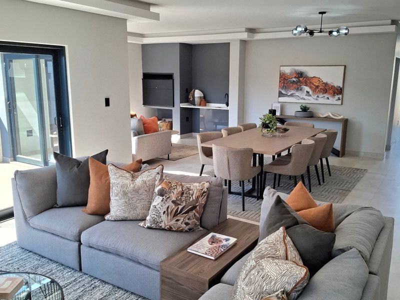Spacious open-plan living and dining area featuring modern tiled floors, recessed ceiling lighting, a built-in fireplace, and large sliding doors leading to the outdoors.