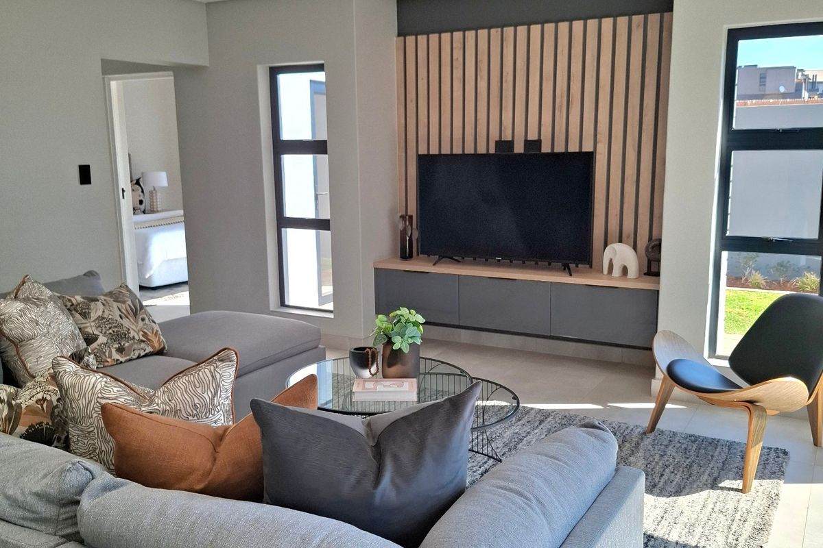 Modern living room featuring a timber slat feature wall, built-in media console, recessed ceiling lighting, and large aluminium windows.