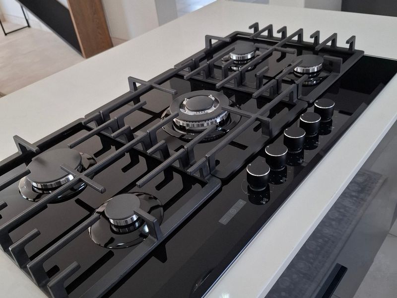 Modern kitchen island featuring a sleek black AEG gas cooktop set into a high-quality stone countertop with contemporary cabinetry.
