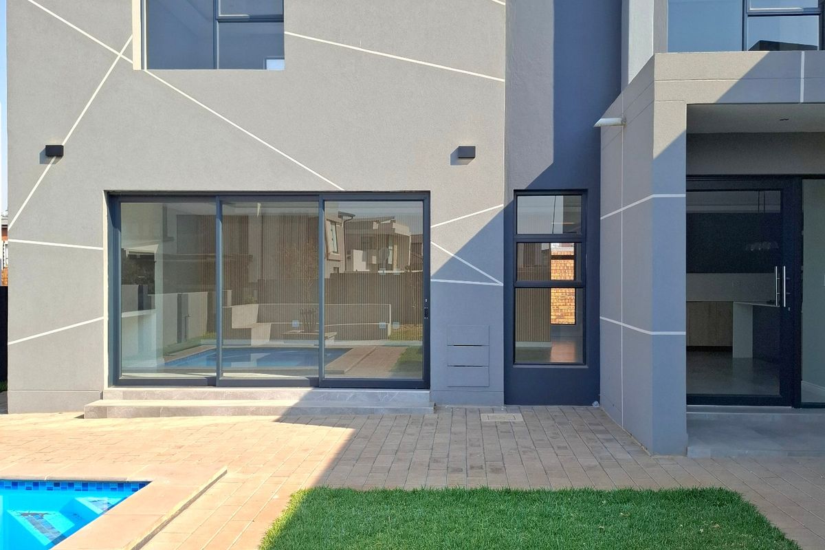 Modern rear exterior view featuring a contemporary facade, paved patio area, and a swimming pool with clean architectural lines.
