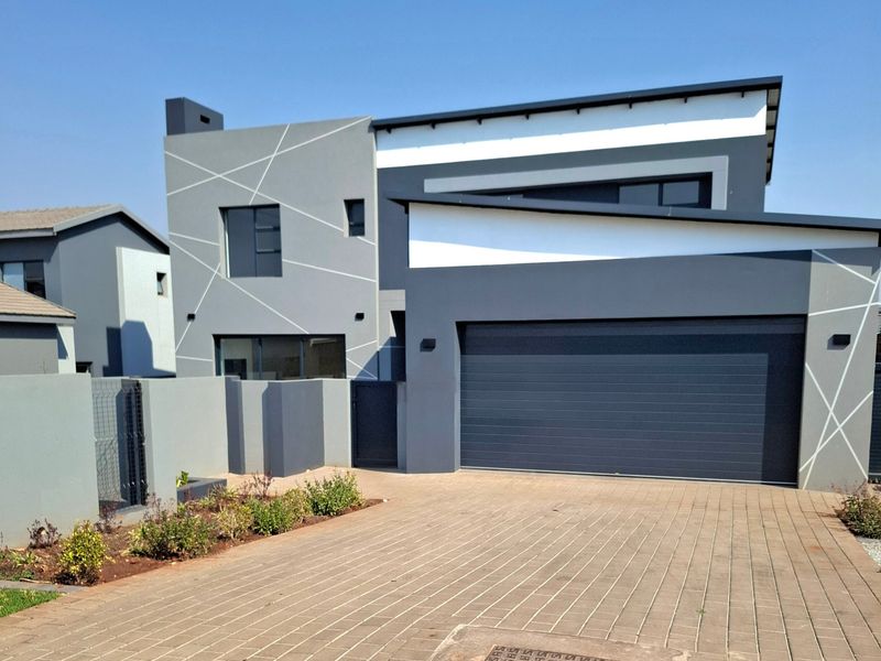 Modern double-storey residential property featuring a contemporary grey and white facade, paved driveway, and a secure automated garage.