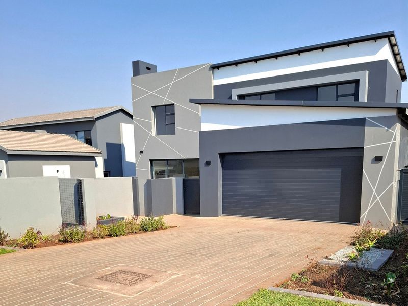 Modern double-storey residential property featuring a contemporary grey and white facade, paved driveway, and integrated double garage.
