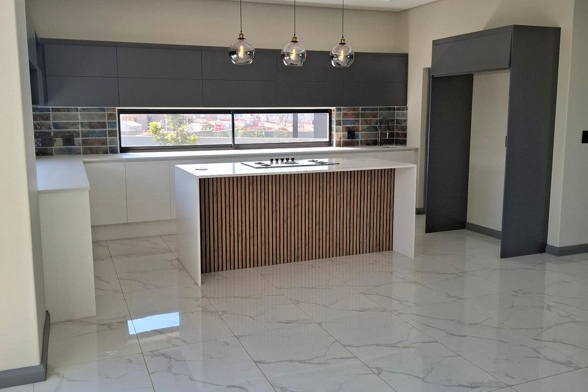 Modern, high-end kitchen featuring a central island with a hob, sleek cabinetry, marble-look tiled flooring, and contemporary recessed ceiling lighting.