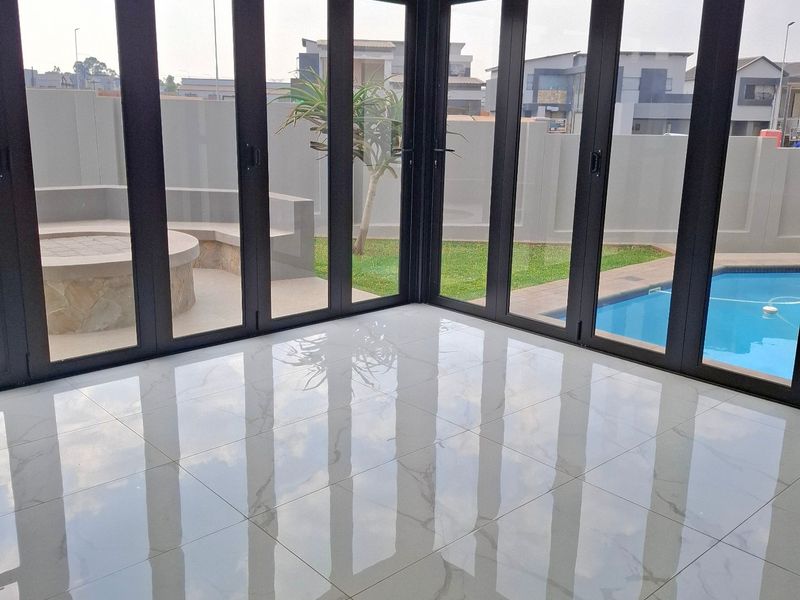 Bright, modern living area featuring large bi-fold doors, polished porcelain tiles, and recessed ceiling lighting, offering seamless access to the outdoor pool and patio.