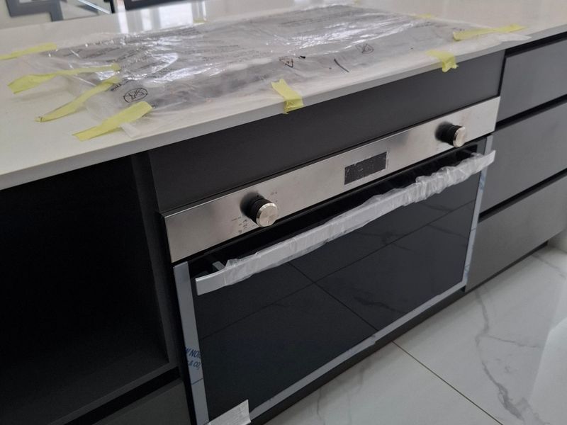 Modern kitchen island featuring a built-in oven, stone countertop, and high-gloss cabinetry, set against a backdrop of polished porcelain flooring and an open-plan layout.