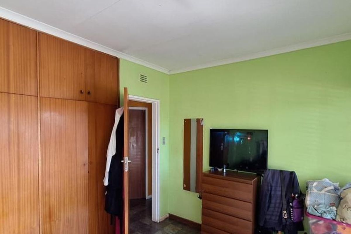 A bedroom featuring floor-to-ceiling built-in wooden cupboards and venetian blinds, offering functional storage space.